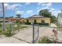 View of a yellow single-story home with a fenced front yard and driveway leading to the house at 450 S Buena Vista Ave, Orlando, FL 32835