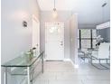 Inviting entryway with white tiled flooring and a modern glass console table, leading to dining area at 7974 Village Green Rd, Orlando, FL 32818