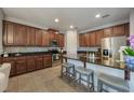 Spacious kitchen featuring dark wood cabinets, granite countertops, stainless steel appliances, and bar seating at 8067 Crushed Pepper Ave, Orlando, FL 32817