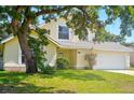 Charming yellow two-story home featuring a well-maintained front yard, arched window, and a two-car garage at 879 Matt Ln, Port Orange, FL 32127