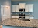Well-lit kitchen features granite countertops, white cabinets, and modern stainless steel appliances at 10126 Beach Port Dr, Winter Garden, FL 34787