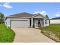 Single-story home featuring a two-car garage, concrete driveway, and a cozy front porch at 123 Zinnia W Ln, Poinciana, FL 34759