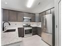 Modern kitchen featuring stainless steel appliances, granite countertops, and stylish gray cabinetry at 13169 Odyssey Lake Way, Orlando, FL 32826