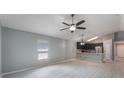 Spacious living room with light gray flooring, a ceiling fan, and views of the modern kitchen at 13169 Odyssey Lake Way, Orlando, FL 32826
