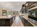 Modern kitchen with dark cabinetry, an oversized island, stainless steel appliances, and recessed lighting at 14516 Sunbridge Cir, Winter Garden, FL 34787