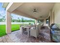 Inviting covered patio with brick flooring, ceiling fans, a dining table, and outdoor grill at 14516 Sunbridge Cir, Winter Garden, FL 34787