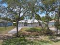 Frontal view of a cozy, single-story home with a metal roof, carport, and mature trees at 160 Chestnut Ave, Orange City, FL 32763