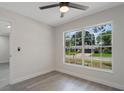A brightly lit bedroom with gray wood flooring, fresh paint, a ceiling fan, and a large window at 1633 Pinehurst Dr, Casselberry, FL 32707
