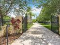 Long driveway through a gated entrance to the home surrounded by lush trees and landscaping at 19123 Sheldon St, Orlando, FL 32833