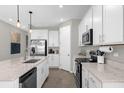 Modern kitchen featuring white cabinets, quartz countertops, stainless steel appliances, and tile flooring at 284 White Heron Way, St Cloud, FL 34772