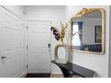 Inviting entryway with a decorative mirror, console table, vase with floral arrangement, and white door at 30245 Cheval St, Mount Dora, FL 32757