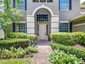 Close-up of a home's arched front entrance surrounded by white flowers and lush foliage at 3213 Kentshire Blvd, Ocoee, FL 34761