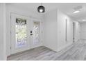 Bright entryway featuring elegant glass double doors and light gray wood-look floors flowing into a hallway at 322 Shadow Oak Dr, Casselberry, FL 32707