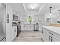 Modern kitchen featuring stainless steel appliances, white cabinets, quartz countertops, and wood-look floors at 322 Shadow Oak Dr, Casselberry, FL 32707