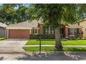 Inviting one-story home featuring a lush green lawn and mature shade tree in a peaceful neighborhood at 356 Via Tuscany Loop, Lake Mary, FL 32746