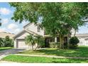 Charming two-story home with a manicured lawn and mature tree providing shade to the entrance at 4208 Lugano Ct, Kissimmee, FL 34746