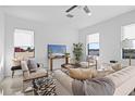 Bright living room with large windows, neutral walls, modern furnishings, and a ceiling fan at 6411 Chorus Dr, Mascotte, FL 34753