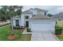 Beautiful home with a two-car garage, lush landscaping, and a prominent palm tree enhances curb appeal at 8100 Fan Palm Way, Kissimmee, FL 34747