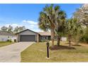 Charming single-story home with palm trees, a well-maintained lawn, and an attached two-car garage at 15690 Sw 46Th Cir, Ocala, FL 34473