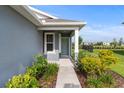 Inviting entrance with a gray front door, sidelight window, and decorative landscaping at 2130 Bur Oak Blvd, St Cloud, FL 34771