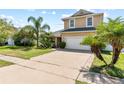 Two-story tan home with a two-car garage, front yard and a long driveway at 2332 Andrews Valley Dr, Kissimmee, FL 34758