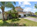 Side view of tan two-story home with attached garage, driveway and landscaped front yard at 2332 Andrews Valley Dr, Kissimmee, FL 34758