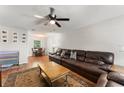 Cozy living room featuring a large leather sofa, ceiling fan, and wood-look flooring at 2710 W County Road 44, Eustis, FL 32726