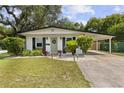 Charming home featuring a lovely light green front door, classic shutters, a covered carport, and beautifully landscaped yard at 280 E Bay Ave, Longwood, FL 32750