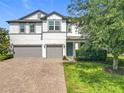 Inviting two-story home featuring a green lawn and a brick driveway, adding to its overall aesthetic appeal at 3184 Pinenut Dr, Apopka, FL 32712