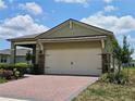 Exterior of home featuring a two-car garage with brick accents and neatly trimmed landscaping at 3371 Yellowtop Loop, Clermont, FL 34714