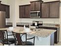 Modern kitchen featuring dark wood cabinets, granite countertops, and stainless steel appliances at 3371 Yellowtop Loop, Clermont, FL 34714