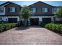 Townhouse with brick driveway leading to a one-car garage, lush landscaping and welcoming entryway at 391 Cape Honeysuckle Pl, Sanford, FL 32771