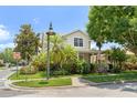 Landscaped corner lot with a charming two-story home, surrounded by lush greenery and mature trees at 7003 Cupseed Ln, Harmony, FL 34773