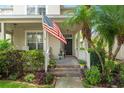 Inviting front porch with brick steps, colorful flowers, and an American flag creating a warm welcome at 7003 Cupseed Ln, Harmony, FL 34773