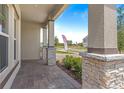 Covered front porch showcasing stone accents, brick flooring, and exterior columns at 1257 Champions Dr, Daytona Beach, FL 32124