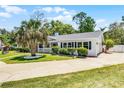 Charming white brick home featuring mature trees, manicured shrubs, and a side driveway for convenience at 174 Pine Grove Ct, Daytona Beach, FL 32119