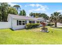 Corner view of a delightful white brick home featuring a decorative wishing well and lush green lawn at 174 Pine Grove Ct, Daytona Beach, FL 32119
