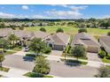 Aerial view of several homes with tan roofs and a large golf course in the background at 2233 Antilles Club Dr, Kissimmee, FL 34747