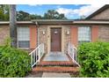 Close-up of a brick home entrance with peach shutters and well-maintained landscaping at 416 Banyon Tree Cir # 108, Maitland, FL 32751