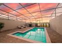 Beautiful screened pool with lounge chairs, grill, and sunset views at 7577 Oak Spring Ln, Davenport, FL 33837