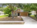 Single-Gathering home with a well-manicured lawn, beautiful trees, and a welcoming front door and a two-car garage at 805 Gordonia Ct, Deland, FL 32724