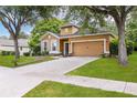 Single-Gathering home with a well-manicured lawn, beautiful trees, and a welcoming front door and a two-car garage at 805 Gordonia Ct, Deland, FL 32724