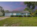 Charming light blue one-story home with a well-manicured front yard and lovely landscaping at 8121 Via Bonita, Sanford, FL 32771
