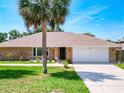 Well-maintained brick home featuring a two-car garage and lush, green lawn at 1233 Gladstone Dr, Deltona, FL 32725
