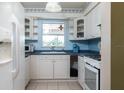 A cozy kitchen featuring white cabinets, blue countertops, and a window overlooking a leafy view at 1389 Gainesville Ln, Deltona, FL 32725