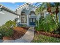Close up of home's entrance with double blue doors, pillars and well maintained landscaping at 14131 Islamorada Dr, Orlando, FL 32837