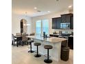 Modern kitchen features a breakfast bar with granite countertops, stainless steel appliances, and dark cabinetry with lots of natural light at 16391 Admirals Cove Ln, Winter Garden, FL 34787