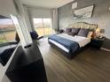 Modern bedroom with large window, grey accent wall, king bed with plush pillows, desk, chair, and wood-look flooring at 225 Celebration Pl # 527, Kissimmee, FL 34747
