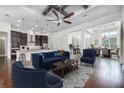 Open-concept living room featuring hardwood floors, modern furniture, a ceiling fan, and seamless flow to kitchen and dining areas at 25859 Crossings Bluff Ln, Sorrento, FL 32776