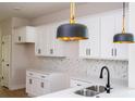 Bright kitchen featuring white cabinets, marble backsplash, stainless steel sink, and modern pendant lighting at 33 W 7Th St, Apopka, FL 32703